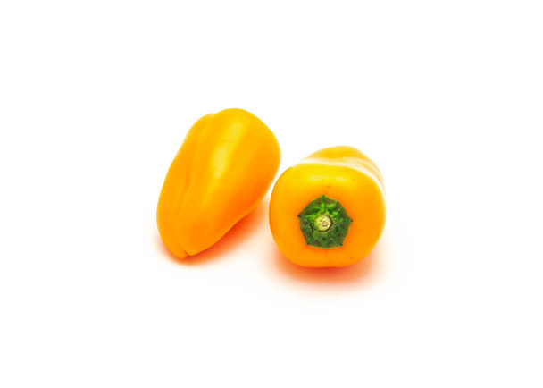 Due vivaci mini peperoni arancioni si isolano su sfondo bianco. Minuscoli mini snack peperoni sono più dolci della media peperone. - Foto, immagini