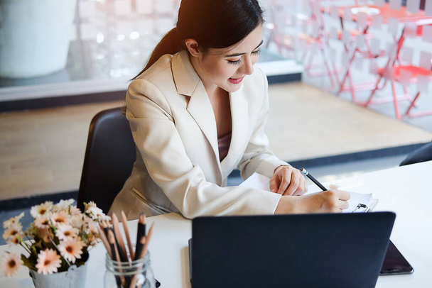 Konzept Geschäftsfrau arbeiten und Menschen glücklich Geschäftsfrau oder kreative Büroangestellte mit Computern Schreiben zu Notizbuch mit Dokumenten und Laptop. - Foto, Bild