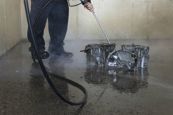 A man cleaning engine block with a power washer at the car wash - Foto, Bild