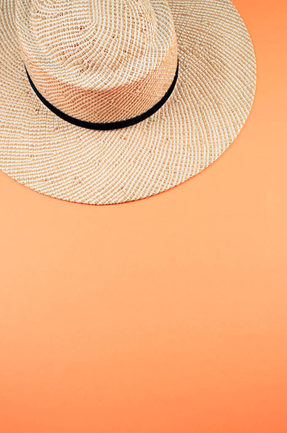 A vertical shot of a straw hat with black ribbon isolated on an orange background - Fotografie, Obrázek