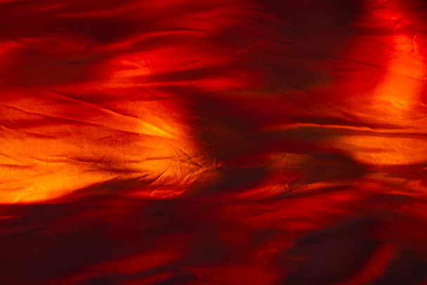 Orange backlit fabric. Fabric imitating fire. Orange background. Red fabric texture. - Foto, Imagem