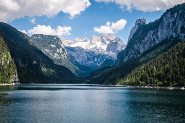 A beautiful view of Lake Gosauseen in Dachstein, Austria surrounded by lush trees and snowy mountains - Foto, Imagem