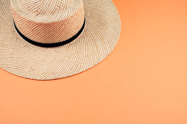 A high angle shot of a straw hat with black ribbon isolated on an orange background - Foto, Imagen