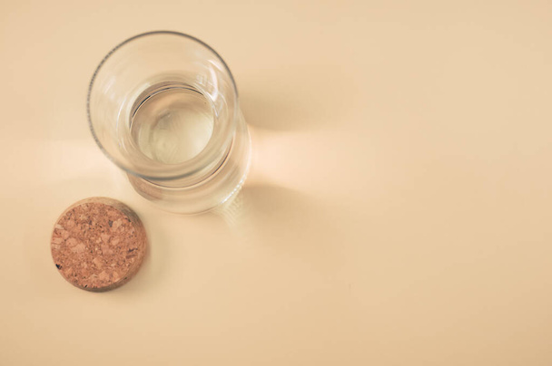 A top view of a clear glass bottle with cork stopper isolated on a brown background - Fotoğraf, Görsel