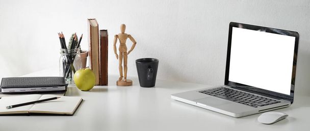 Vista frontal computador portátil, calculadora, livros e xícara de café na mesa branca com parede de concreto. - Foto, Imagem