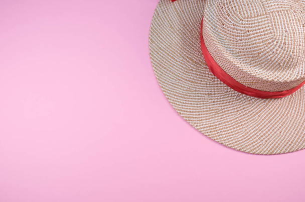 A top view of a straw hat with red ribbon isolated on a pink background - Φωτογραφία, εικόνα