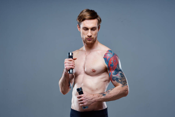 Веселый мужчина с надутой мускулистой татуировкой на руках - Фото, изображение