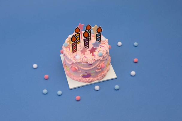A closeup of a pink birthday cake on a blue surface - Foto, Imagen
