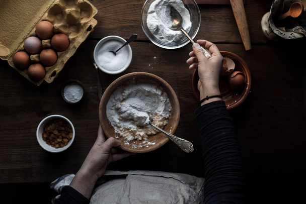 A cook baking pastry in the kitchen with different ingredients on the table - Foto, afbeelding