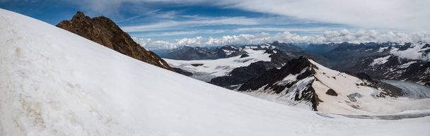 A beautiful panoramic shot of Weisskugel with snow covering its peak under a bright sky in Italy/Austria - Photo, Image