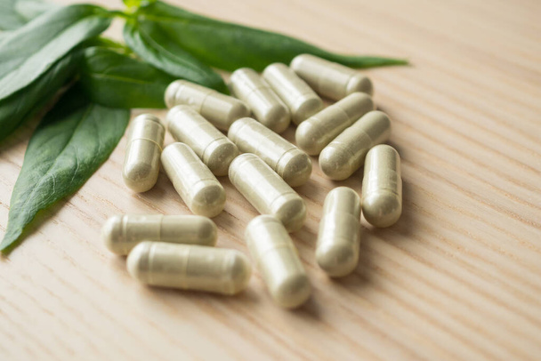 Herbal medicine capsules with Andrographis paniculata leaf on wood table - Photo, Image