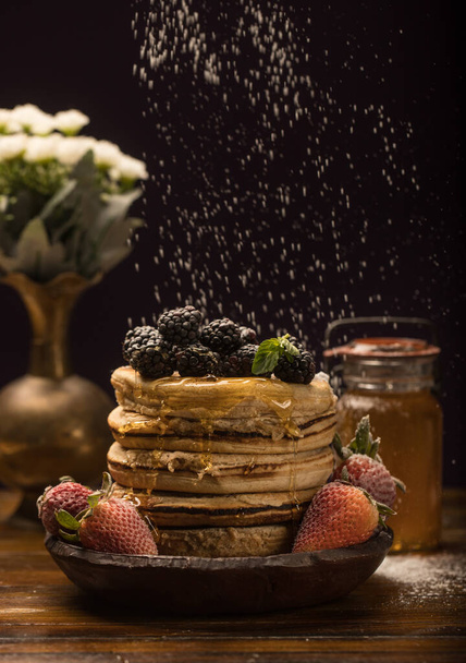 A vertical shot of delicious pancakes with berries on black background - Valokuva, kuva