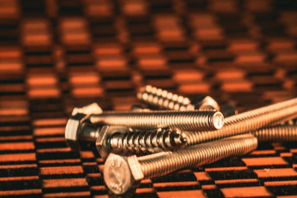 A closeup shot of screws on an orange-black background - Foto, afbeelding