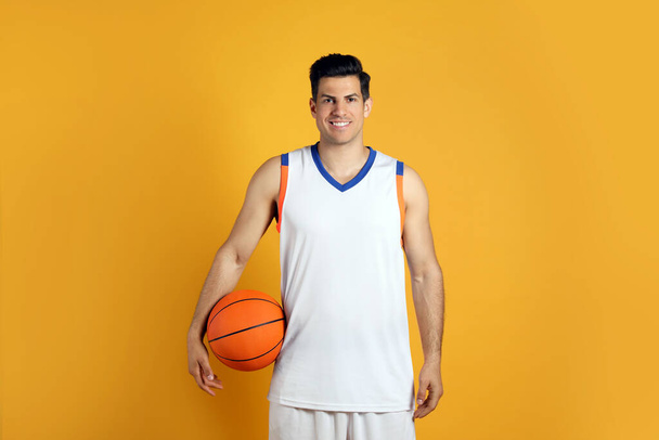 Basketball player with ball on yellow background - Fotó, kép