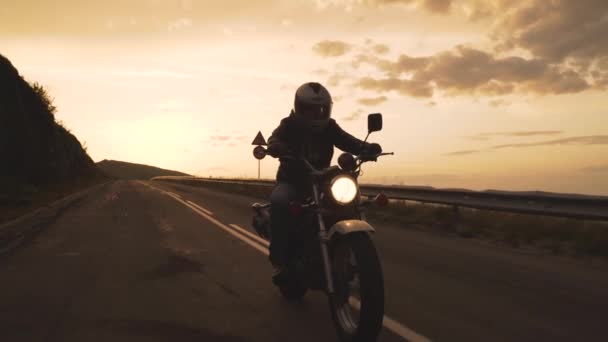 Σιλουέτα ποδηλάτης ιππασία vintage μοτοσικλέτα σε επαρχιακό δρόμο στο ηλιοβασίλεμα - Πλάνα, βίντεο