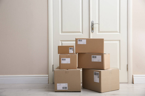 Stacked parcels near door on floor, space for text. Delivery service - Foto, Imagem