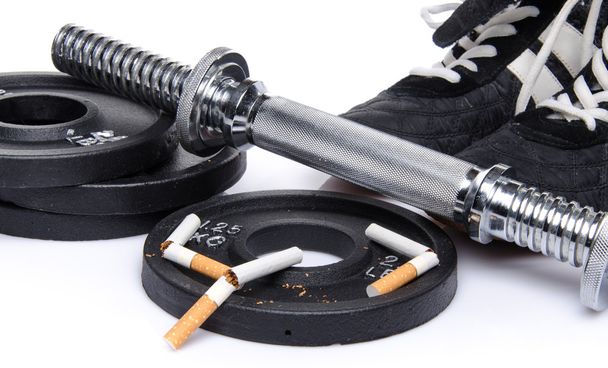 Dumbells, sapatos de fitness com cigarros quebrados
 - Foto, Imagem