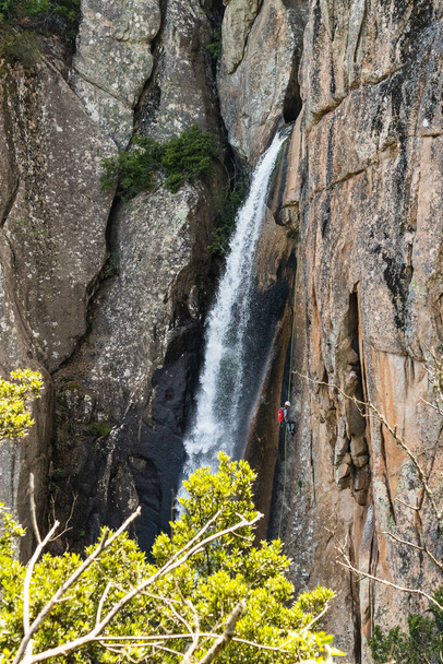A vertical shot of a person climbing a waterfall - Zdjęcie, obraz