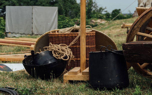 A closeup shot of big black containers and horse chariot parts put outside on the grass - Foto, Imagem