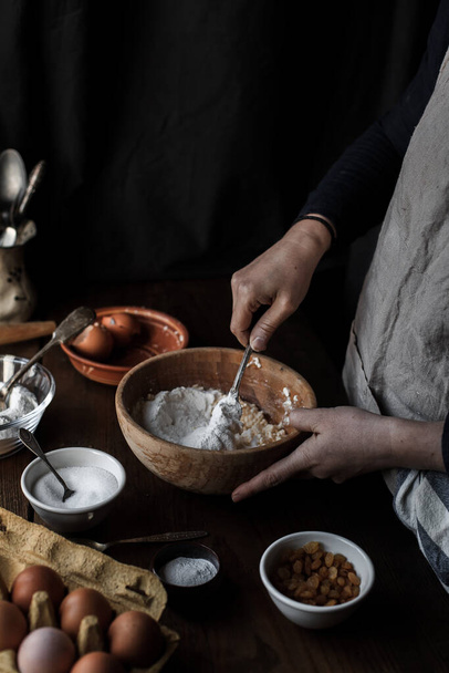 A cook baking pastry in the kitchen with different ingredients on the table - Фото, зображення
