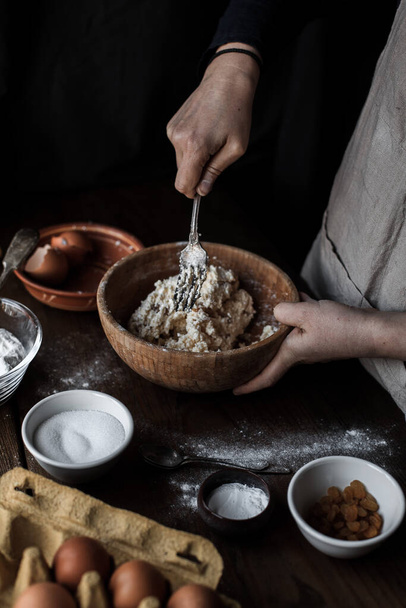 A cook baking pastry in the kitchen with different ingredients on the table - Fotó, kép