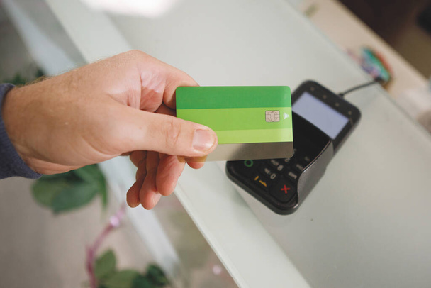 El proceso de pago con una tarjeta bancaria sin contacto con una tarjeta de plástico en el terminal de la tienda. - Foto, imagen