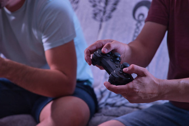 Detalhe da mão do homem segurando um controle de console de vídeo enquanto joga com um amigo. - Foto, Imagem