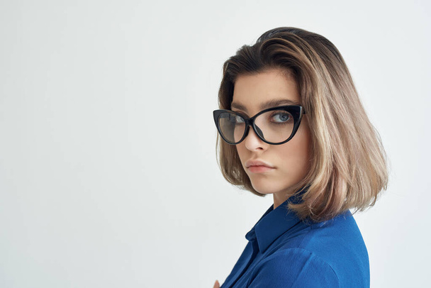 elegante vrouw draagt bril blauw shirt studio - Foto, afbeelding
