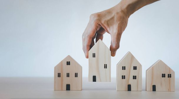 Hand touch Mini dom drewniany model od modelu na drewnianym stole, Planowanie kupić nieruchomości, Planowanie kupić nieruchomość i wybrać najlepsze. praca w domu i pobyt w domu koncepcja. - Zdjęcie, obraz