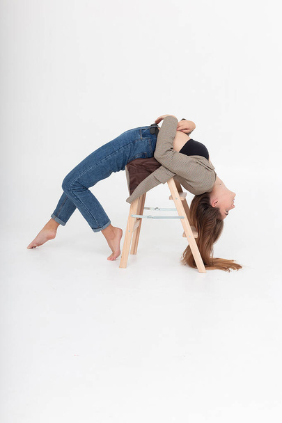 skinny female lying in bridge position on wooden ladder at studio with bare feet - Fotoğraf, Görsel