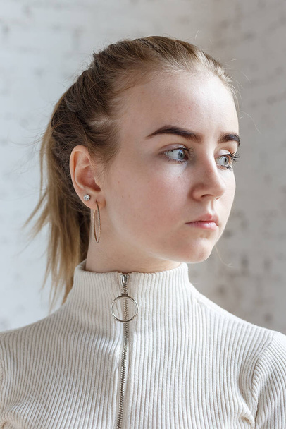 closeup portrait of thoughtful teen model with blue eyes wearing white sweater - Photo, Image