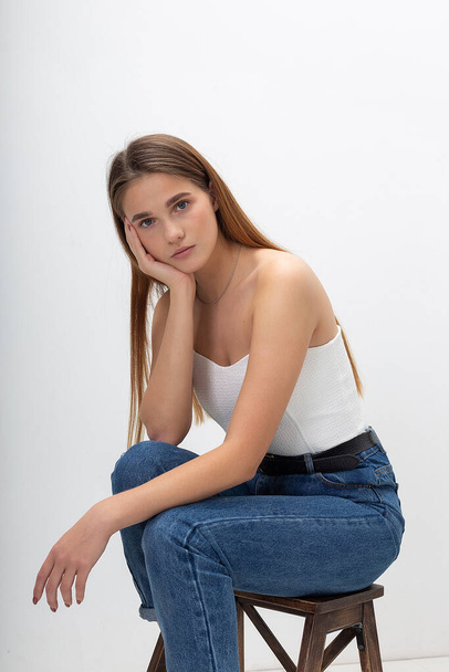 young caucasian woman with long brown hair in in corset, blue jeans at studio - Foto, Imagem
