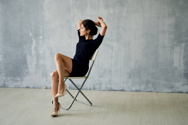 žena v černých šatech sedí na pózujícím křesle Studio Moda luxus - Fotografie, Obrázek