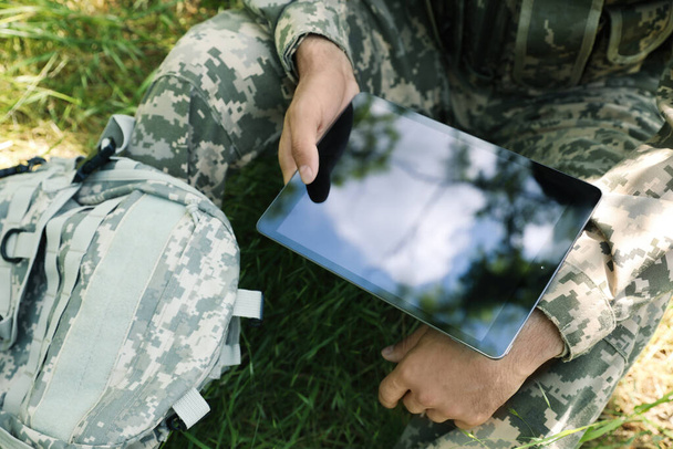 Soldier with backpack using tablet in forest, closeup - Foto, Imagem