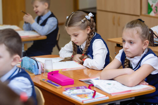 Schulmädchen an ihrem Schreibtisch im Klassenzimmer während des Unterrichts. Grundschulbildung. Selektiver Fokus. - Foto, Bild