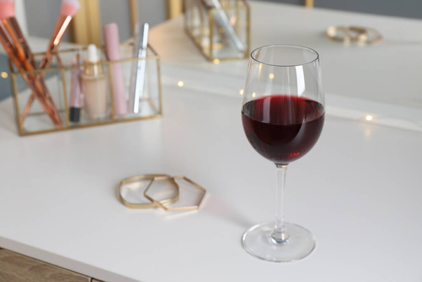 Glass of red wine and jewelry on white table indoors, space for text - Fotó, kép
