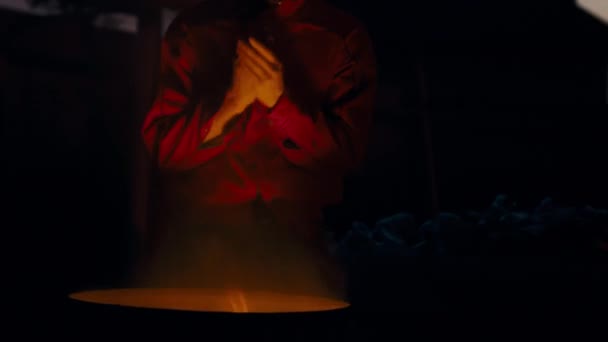 Mann mit Brille und roter Jacke sonnt sich neben brennendem Mülleimer im Gesicht. - Filmmaterial, Video