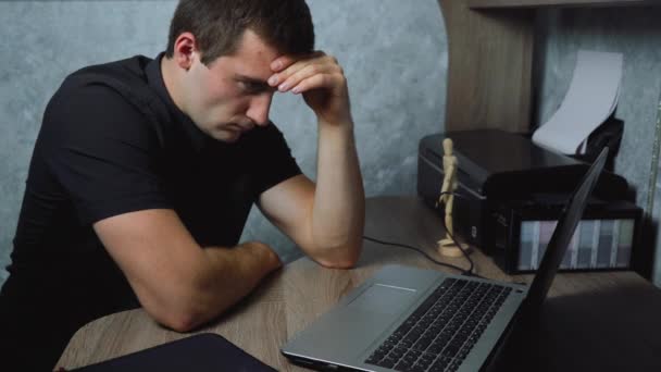 väsynyt mies istuu töissä kannettavan - Materiaali, video