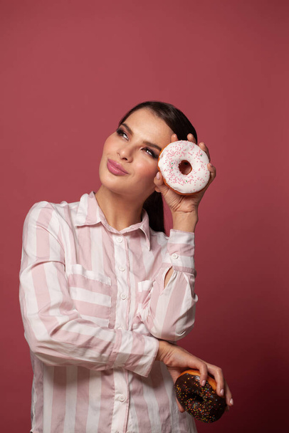Stijlvolle mooie jonge vrouw met donuts op rode achtergrond portret, dieet, dieet, junk food, afslanken en gewichtsverlies concept - Foto, afbeelding