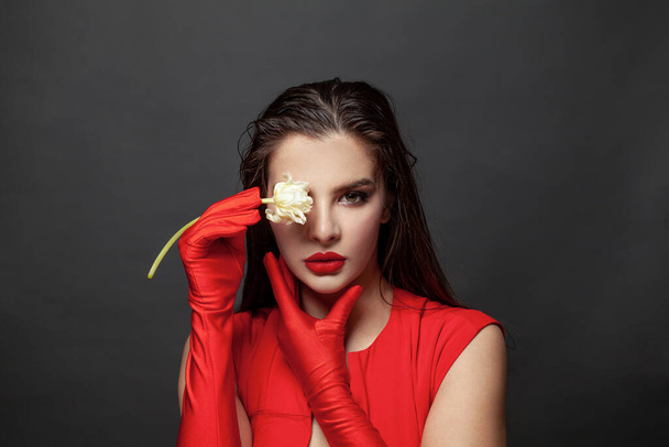 Gorgeous elegant brunette woman wearing fashion red dress and silk gloves on black background - Foto, afbeelding