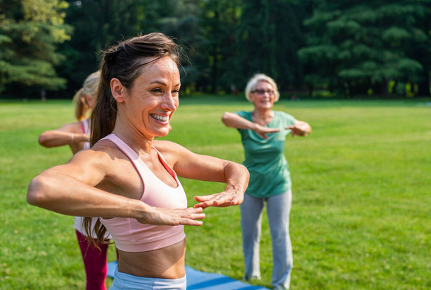 Multiethnic group of senior women training at park with fitness instructor - Active elderly people doing sport in the nature - Фото, зображення