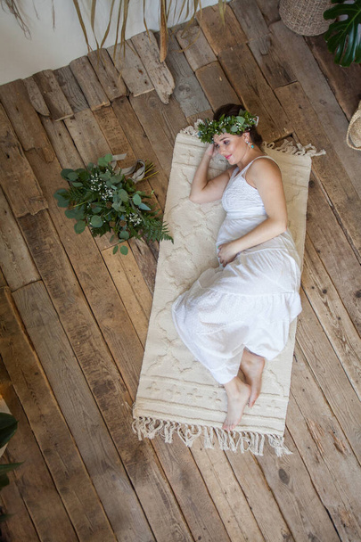 Cute pregnant woman lying on wooden floor indoor, top view - Foto, immagini