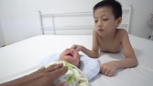 La mano del padre toca al bebé recién nacido llorando. Hermano toca la cabeza del bebé - Metraje, vídeo