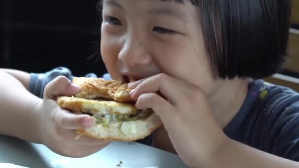 Lächelnde chinesische Kinder essen leckere Hamburger. Junk Food, Fastfood-Konzept - Filmmaterial, Video