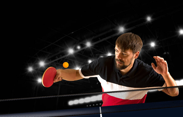 Man playing ping pong on dark background - Фото, изображение