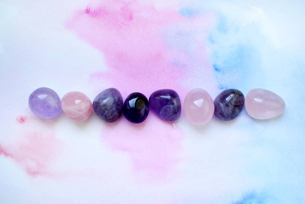 Gems of various colors. Amethyst and rose quartz on blue-pink background. - Photo, image