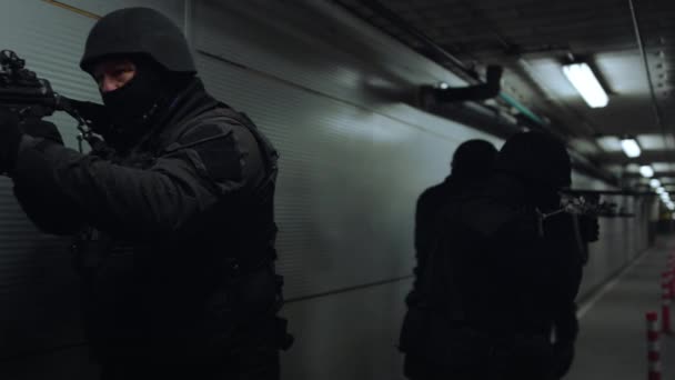 SWAT-ryhmä kävelee pimeässä käytävässä. Erikoisjoukkojen ryhmä osoittaa aseella - Materiaali, video