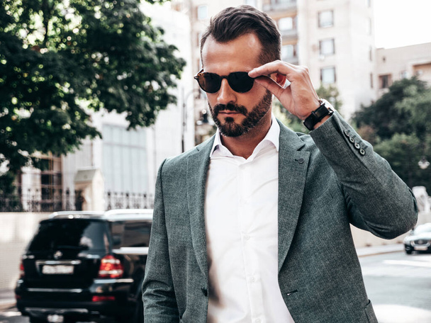 Portrait of handsome confident stylish hipster lambersexual model.Modern man dressed in elegant suit. Fashion male posing in the street background in Europe city at sunset. In sunglasses - Φωτογραφία, εικόνα