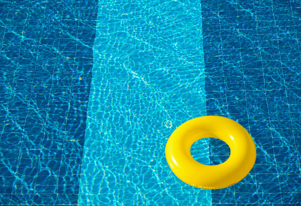Piscina amarela flutuar, anel flutuando em uma piscina azul refrescante - Foto, Imagem
