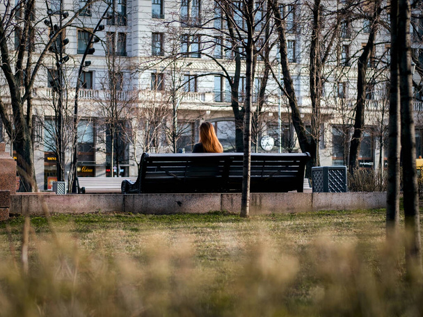 Young redhead lady sitting on a bench - Фото, зображення